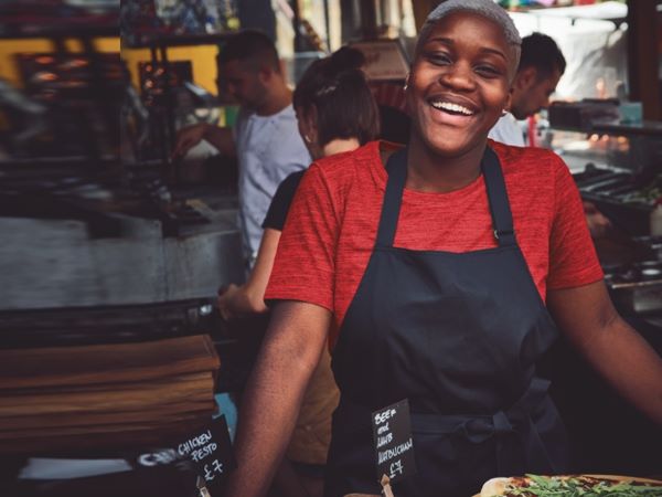 Une employée d'un établissement de street food porte un tablier de cuisine noir.